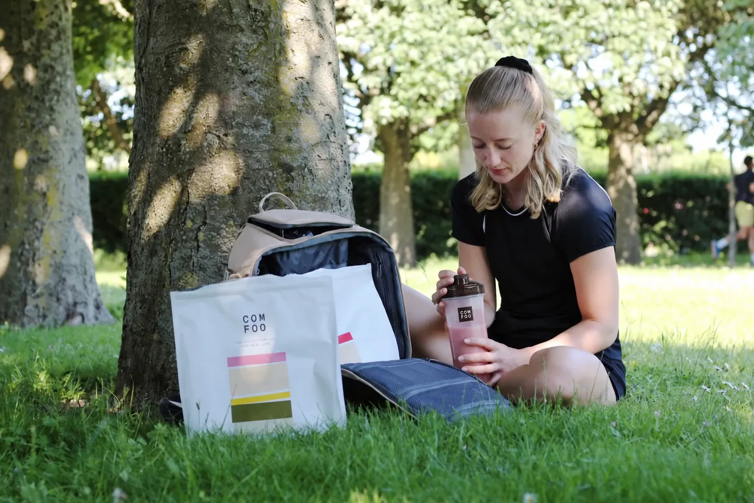 Johanna sitter utomhus med en ComFoo-påse och en shake